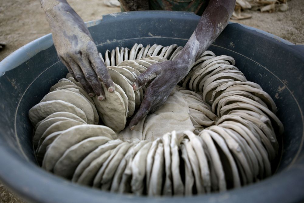Yolen Jeunky arranges dried mud cookies for sale in a bucket in Cite Soleil in Port-au-Prince, Thursday, Nov. 29, 2007. Rising prices and food shortages threaten the nation's fragile stability, and the mud cookies, made of dirt, salt and vegetable shortening, are one of very few options the poorest people have to stave off hunger. (AP Photo/Ariana Cubillos)
